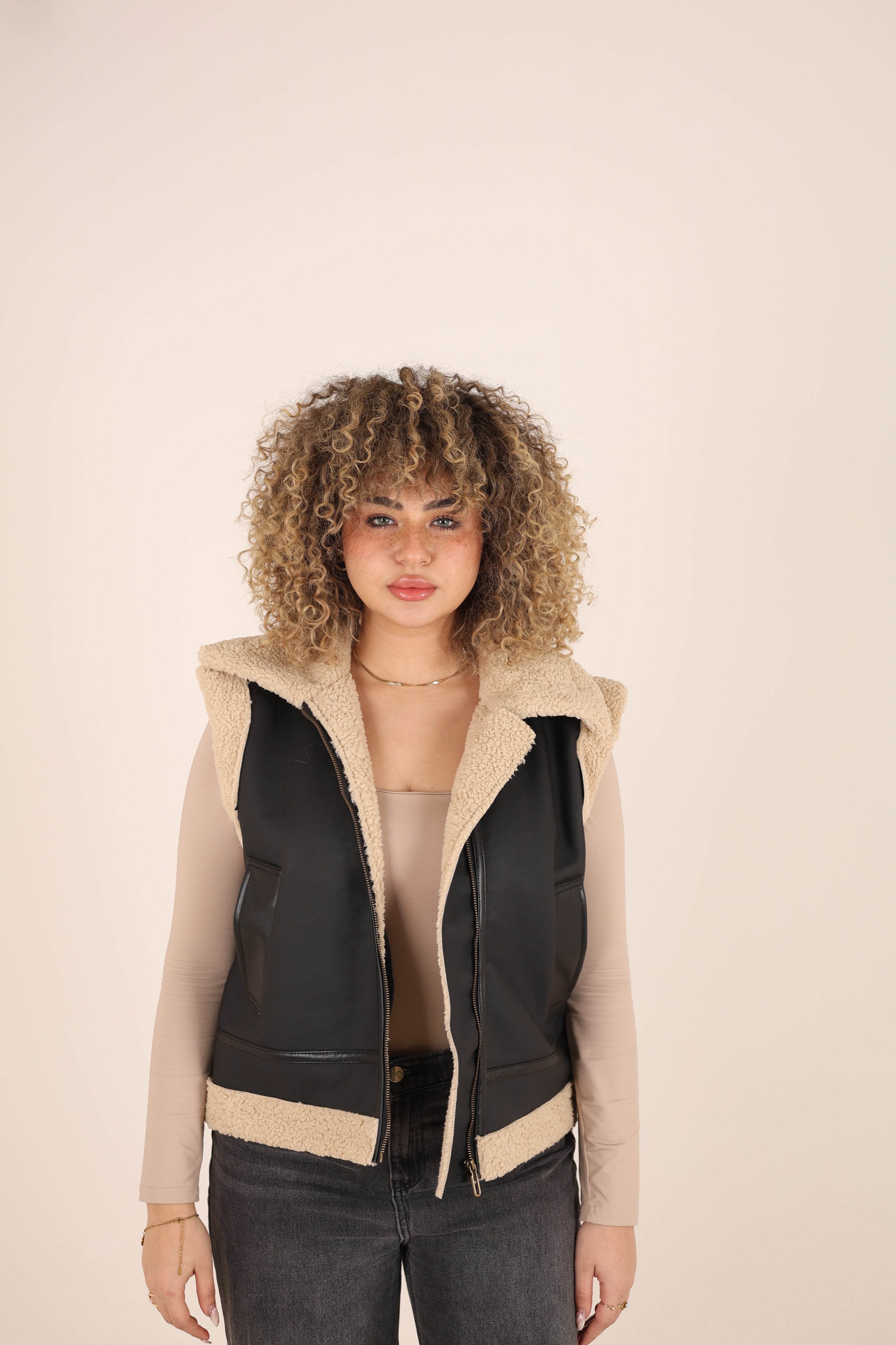 Woman wearing a black and beige outfit on a plain background