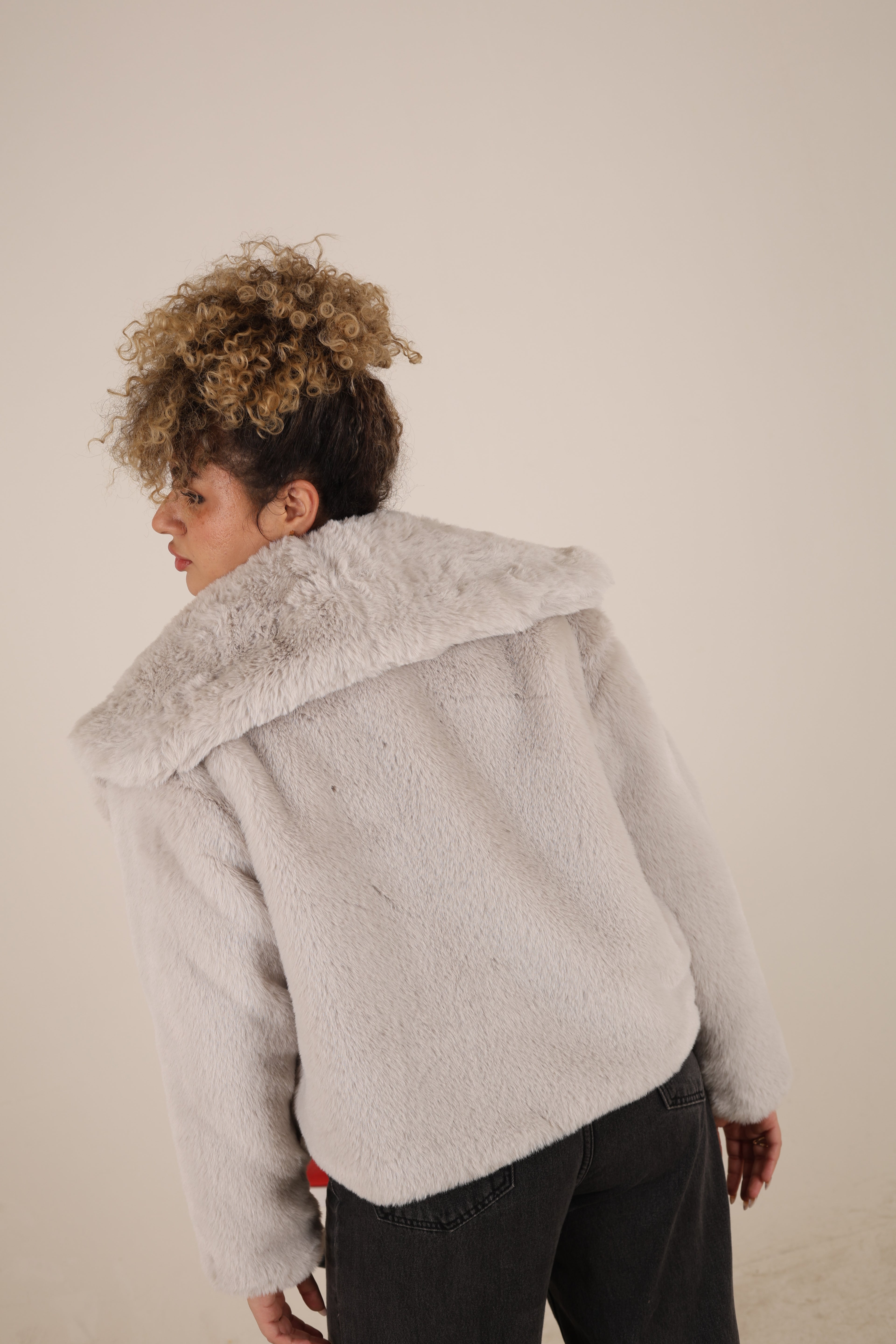 Person wearing a light gray oversized sweater on a plain background