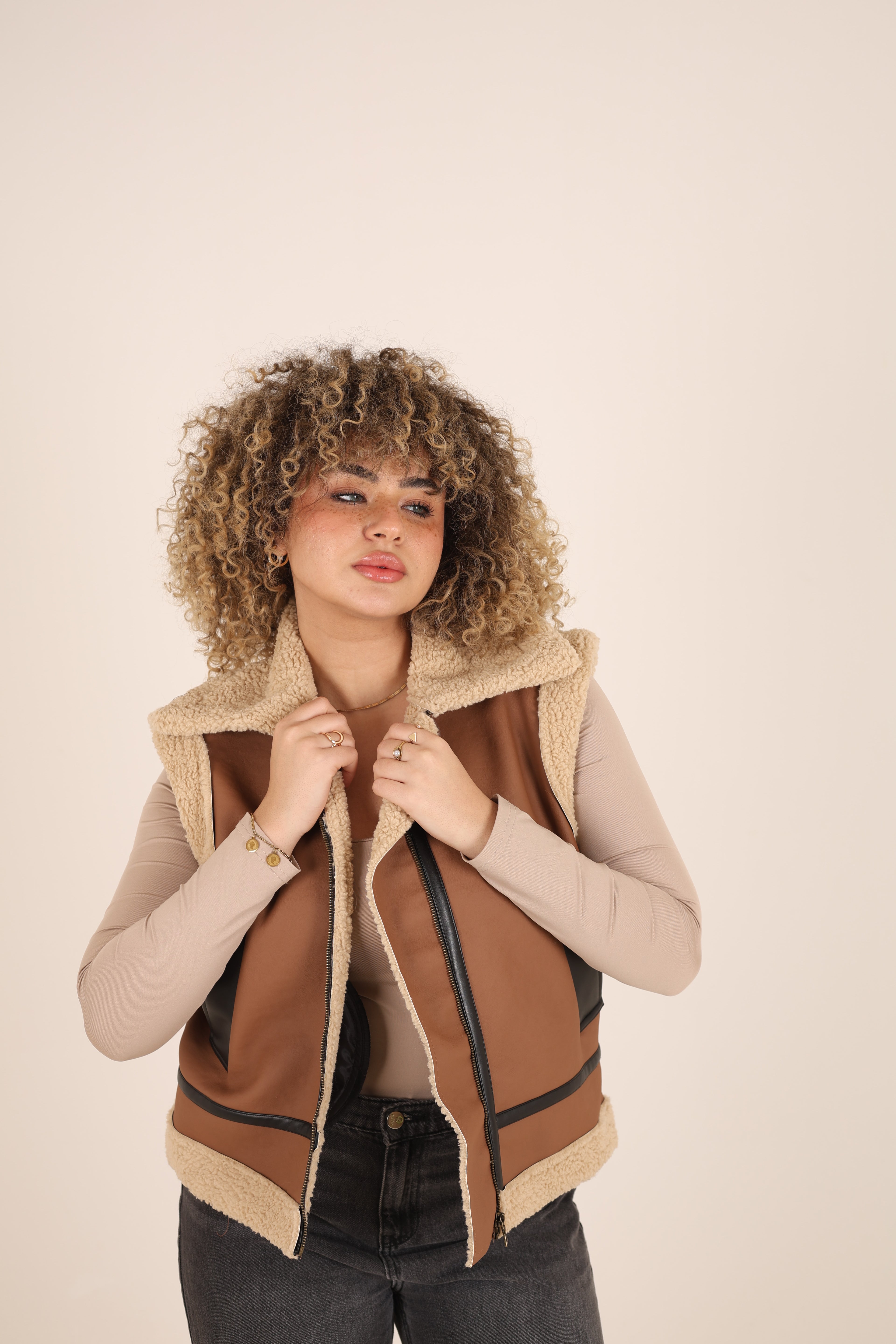 Woman wearing a brown and beige vest on a beige background