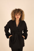 Person wearing a black coat with a beige background
